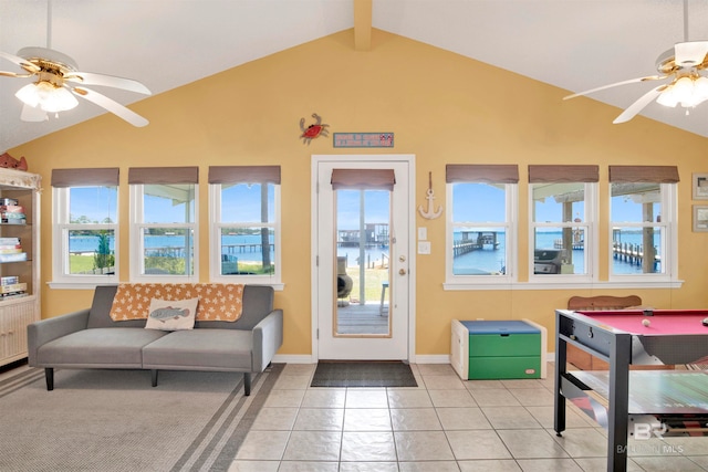 interior space with ceiling fan, lofted ceiling with beams, a water view, and light tile patterned flooring