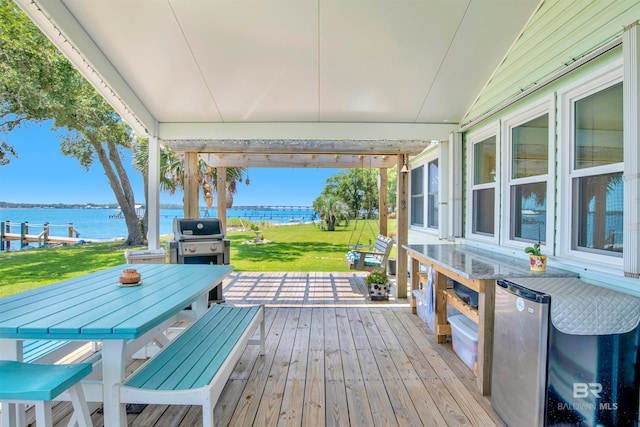 wooden terrace with grilling area, a water view, and a lawn