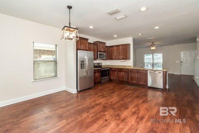 kitchen with kitchen peninsula, stainless steel appliances, dark wood-type flooring, and ceiling fan with notable chandelier