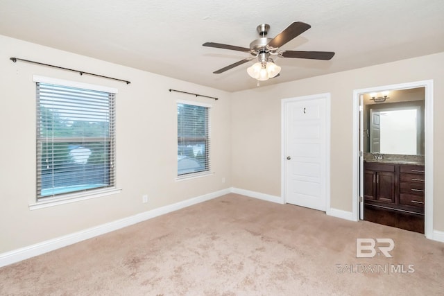 unfurnished bedroom featuring ceiling fan, light carpet, and ensuite bathroom