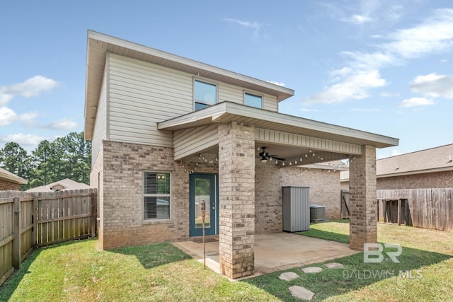 rear view of property featuring a lawn, ceiling fan, central AC unit, and a patio