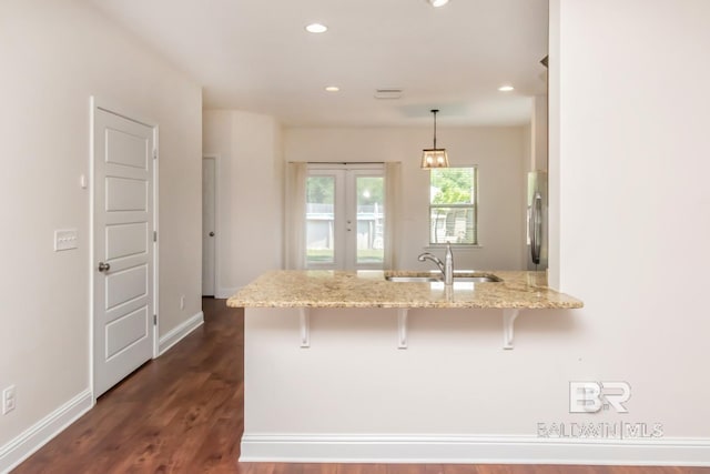 kitchen featuring sink, a breakfast bar area, dark wood-type flooring, stainless steel fridge, and kitchen peninsula