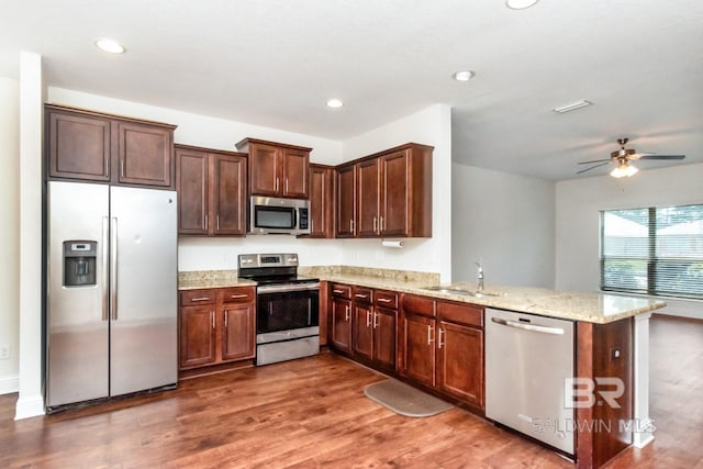 kitchen with ceiling fan, wood-type flooring, sink, kitchen peninsula, and stainless steel appliances