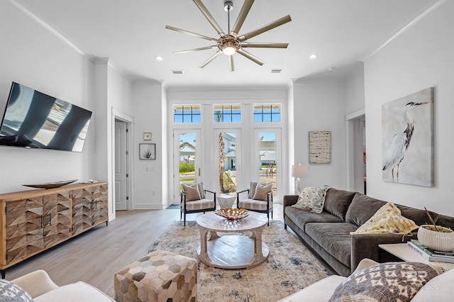 living room featuring ceiling fan, light wood-type flooring, and ornamental molding