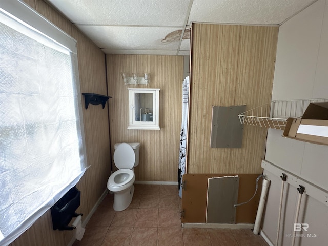 bathroom featuring tile patterned flooring, wooden walls, and toilet