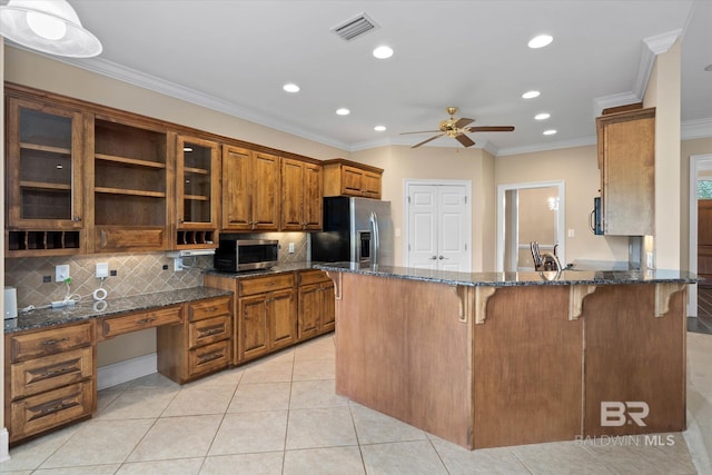 9529 Aspen Cir, Daphne, AL 36527 - kitchen with stainless steel appliances, brown cabinetry, a ceiling fan, a breakfast bar, and decorative backsplash