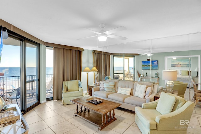 living room featuring ceiling fan, light tile patterned floors, and a water view