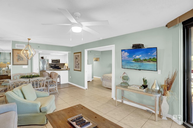 tiled living room with ceiling fan with notable chandelier