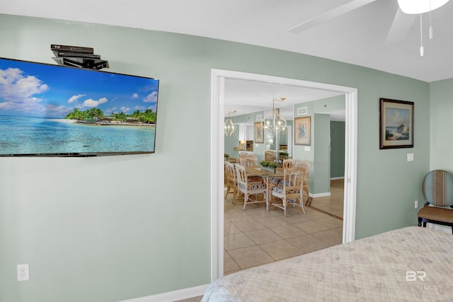 bedroom featuring light tile patterned floors and ceiling fan with notable chandelier