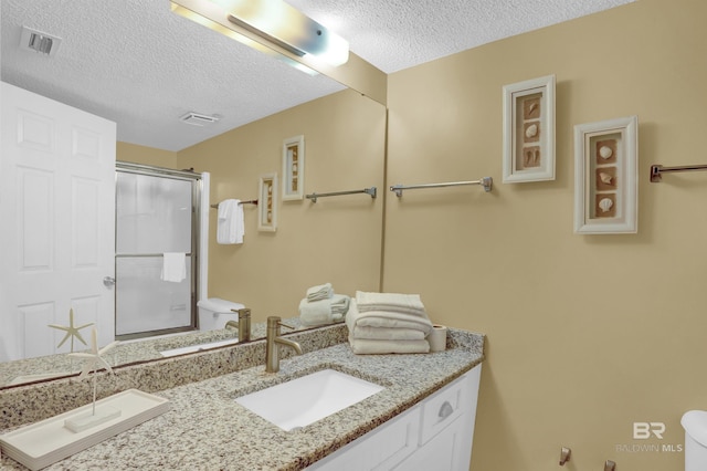 bathroom featuring a textured ceiling, a shower with shower door, and vanity