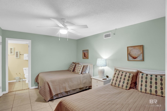 bedroom with ceiling fan, light tile patterned floors, ensuite bathroom, and a textured ceiling