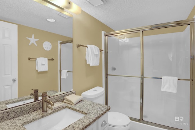 bathroom featuring toilet, vanity, a shower with door, and a textured ceiling