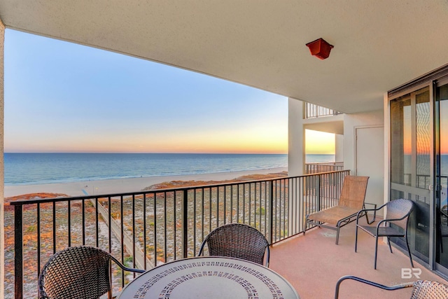 balcony at dusk with a water view and a beach view