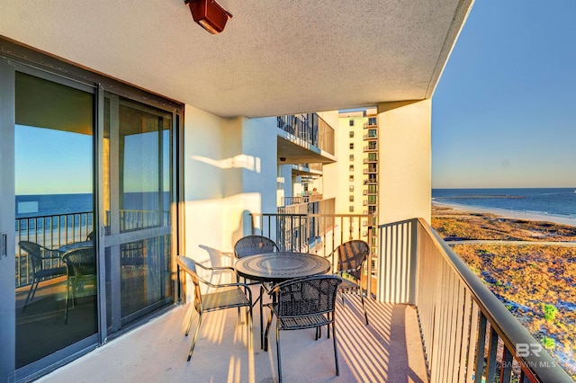 balcony featuring a water view and a beach view