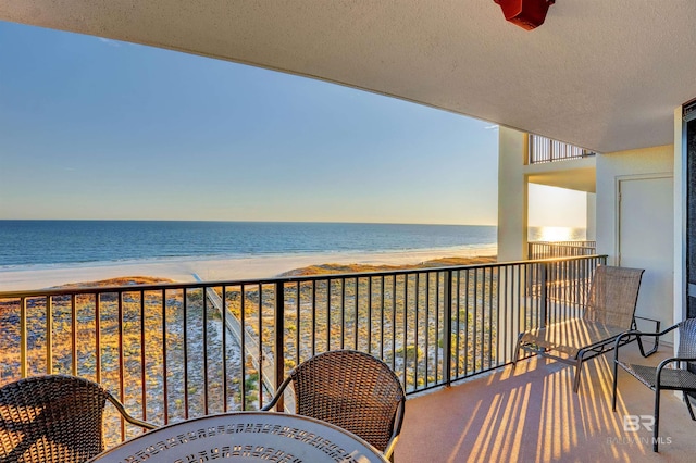 balcony with a water view and a view of the beach