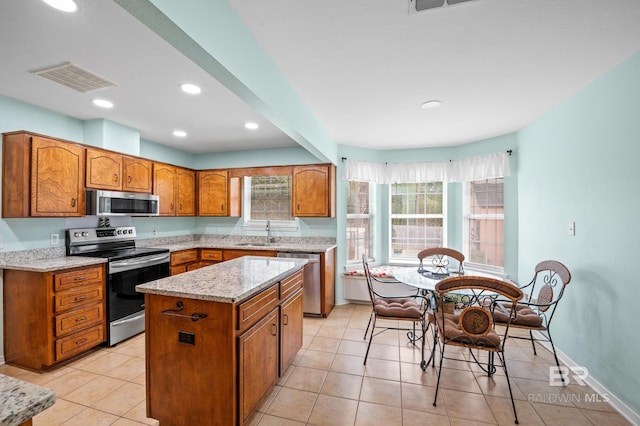 2553 Santa Rosa Dr, Lillian, AL 36549 - kitchen featuring stainless steel appliances, a sink, brown cabinetry, a kitchen island, and healthy amount of natural light