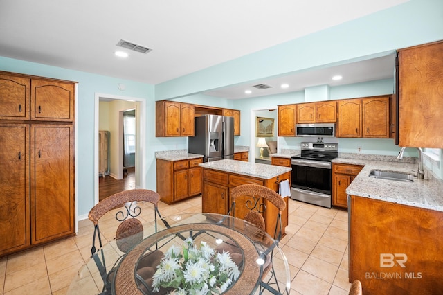 2553 Santa Rosa Dr, Lillian, AL 36549 - kitchen featuring appliances with stainless steel finishes, brown cabinets, light tile patterned floors, light stone counters, and recessed lighting