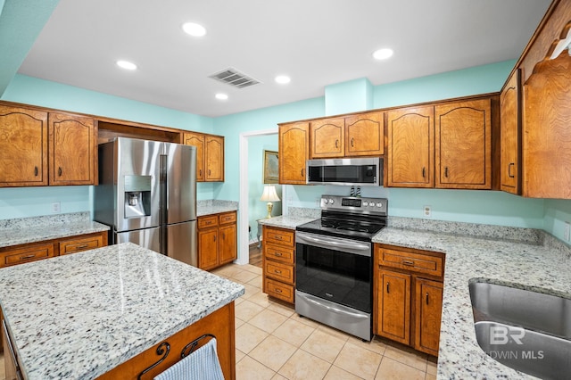 2553 Santa Rosa Dr, Lillian, AL 36549 - kitchen featuring stainless steel appliances, brown cabinetry, light tile patterned floors, and recessed lighting