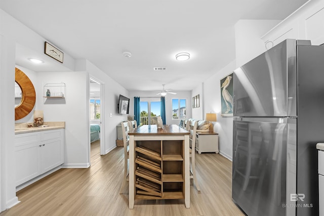 kitchen with ceiling fan, white cabinets, stainless steel refrigerator, and light hardwood / wood-style flooring