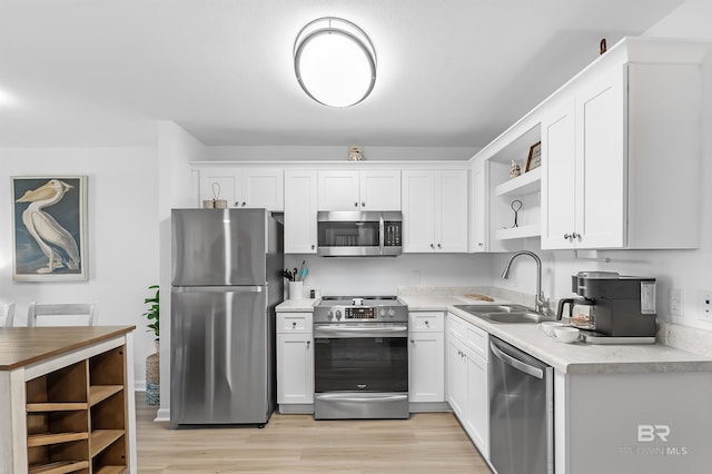 kitchen with light hardwood / wood-style flooring, white cabinets, appliances with stainless steel finishes, and sink