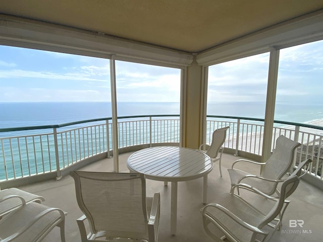 sunroom featuring a water view and a view of the beach