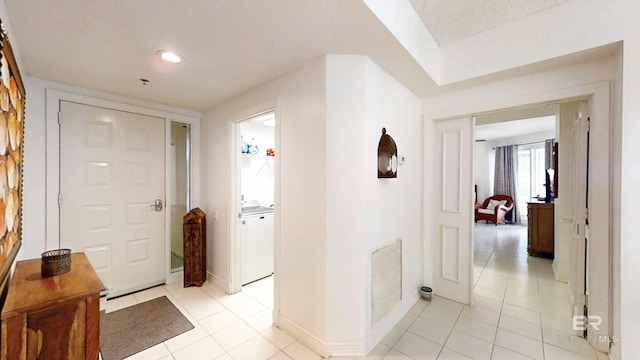 hall featuring washer / clothes dryer and light tile patterned flooring