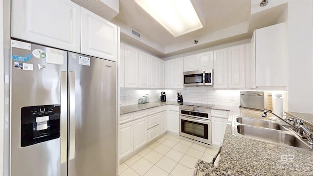 kitchen featuring appliances with stainless steel finishes, tasteful backsplash, sink, white cabinets, and light stone counters