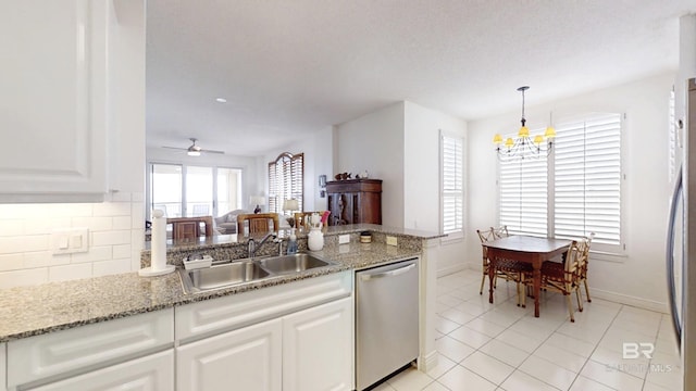 kitchen with tasteful backsplash, white cabinetry, dishwasher, sink, and hanging light fixtures