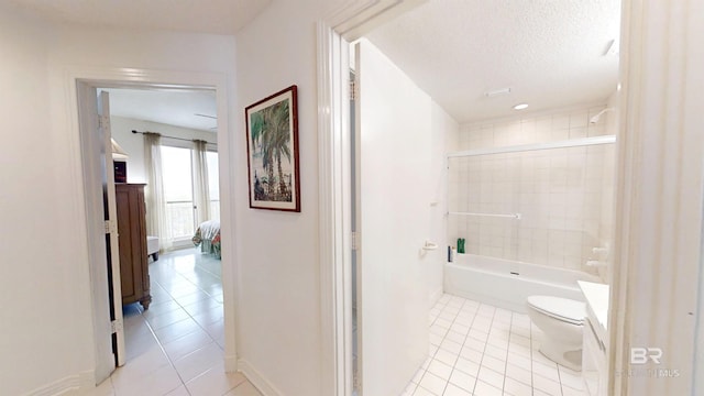 bathroom with tile patterned flooring, a textured ceiling, tiled shower / bath combo, and toilet