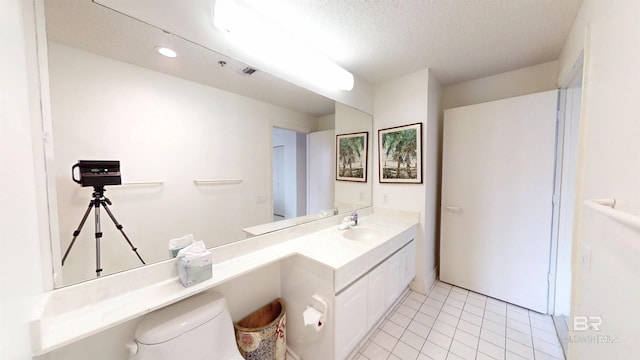 bathroom featuring vanity, toilet, tile patterned flooring, and a textured ceiling