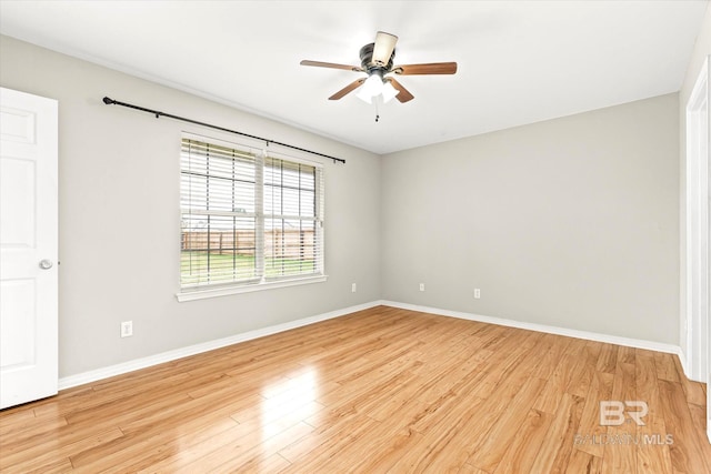 spare room with light wood-type flooring, a ceiling fan, and baseboards