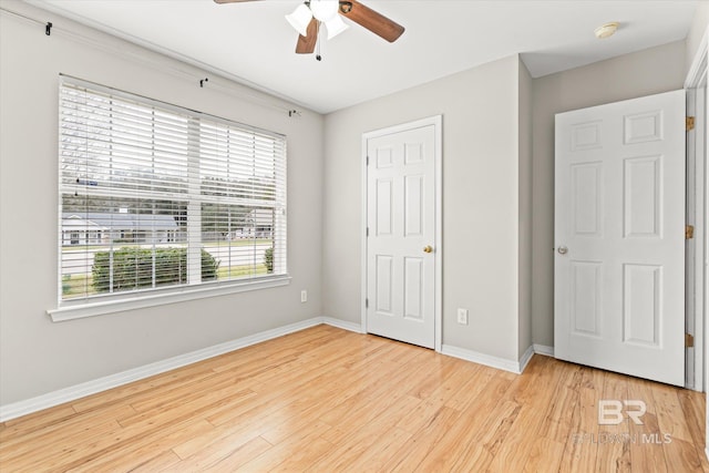 unfurnished bedroom with light wood-type flooring, ceiling fan, and baseboards