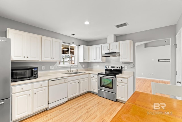 kitchen with appliances with stainless steel finishes, decorative light fixtures, light countertops, white cabinetry, and a sink