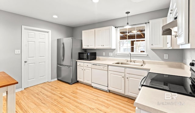 kitchen with hanging light fixtures, light countertops, freestanding refrigerator, range hood, and dishwasher