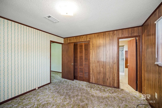 unfurnished bedroom featuring carpet, crown molding, a textured ceiling, and a closet