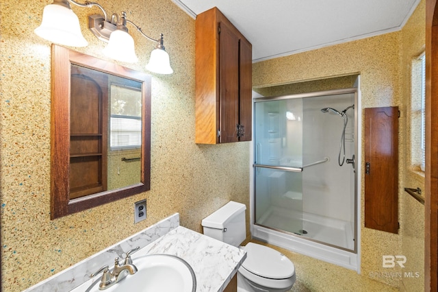 bathroom featuring vanity, crown molding, a shower with shower door, and toilet