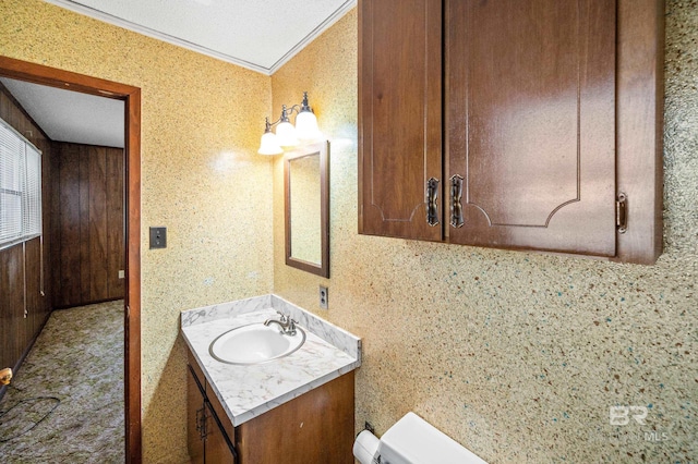 bathroom featuring vanity, crown molding, toilet, and wooden walls