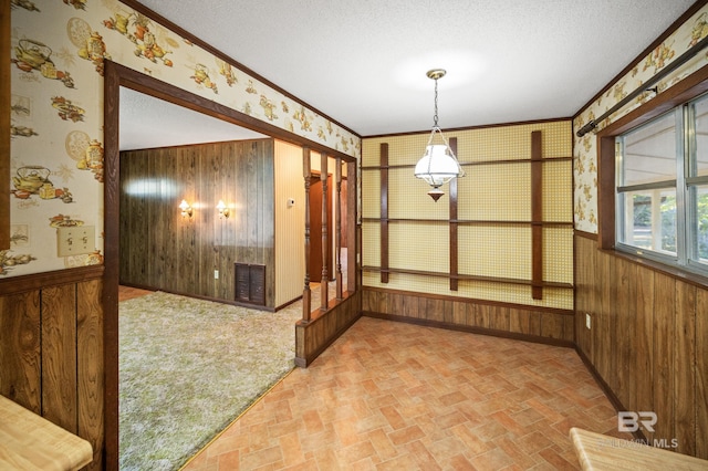 unfurnished dining area with crown molding, a textured ceiling, and wooden walls