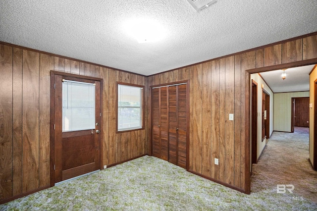 interior space with a textured ceiling and wooden walls