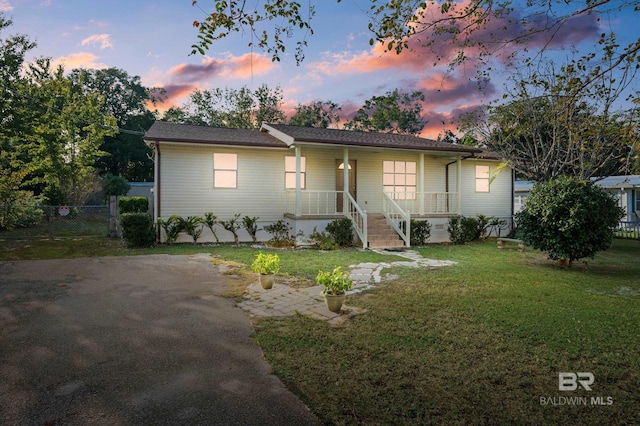 ranch-style home featuring covered porch and a lawn