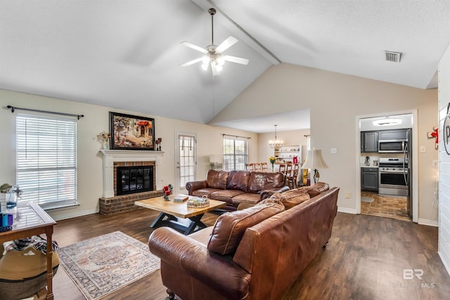 living area featuring lofted ceiling, ceiling fan with notable chandelier, dark wood-style flooring, a fireplace, and visible vents