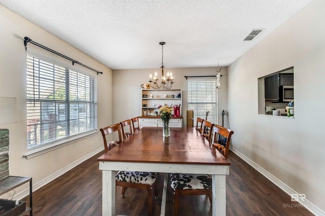 dining room with visible vents, dark wood-style flooring, a textured ceiling, a chandelier, and a wealth of natural light