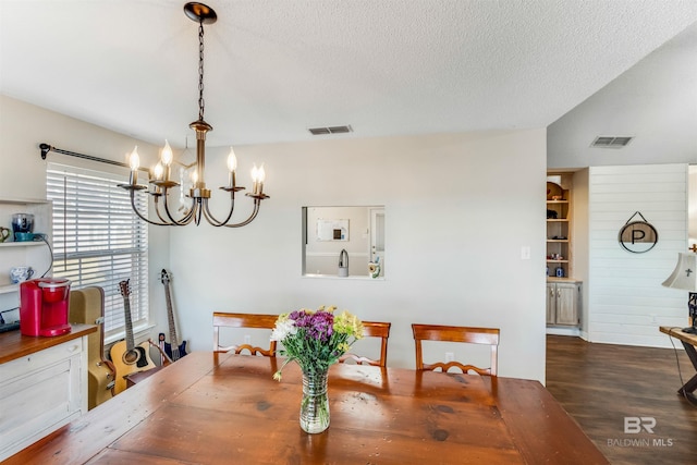 dining area with an inviting chandelier, visible vents, a textured ceiling, and wood finished floors