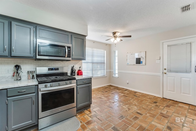 kitchen featuring light countertops, appliances with stainless steel finishes, backsplash, and visible vents