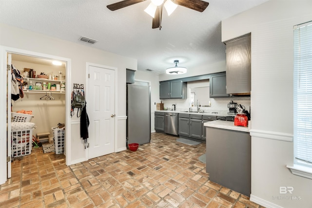 kitchen featuring gray cabinetry, a sink, visible vents, light countertops, and appliances with stainless steel finishes