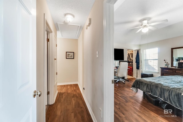 bedroom featuring attic access, a textured ceiling, baseboards, and dark wood-style flooring