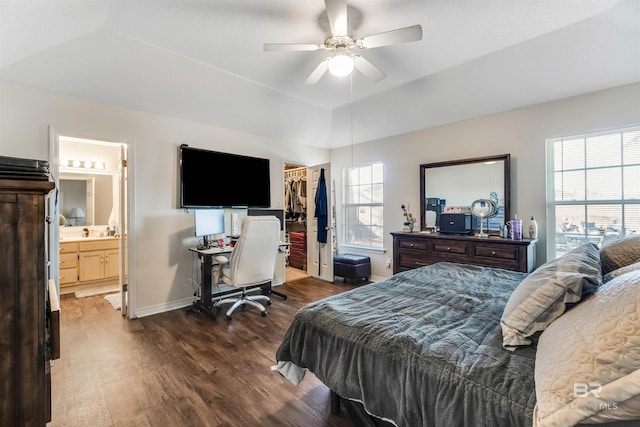 bedroom with baseboards, wood finished floors, a spacious closet, a tray ceiling, and a closet