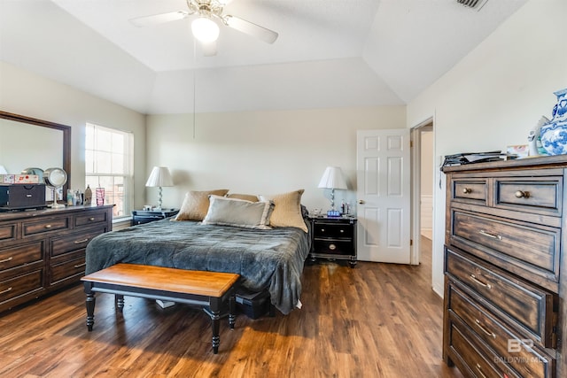 bedroom with a tray ceiling, vaulted ceiling, dark wood finished floors, and ceiling fan