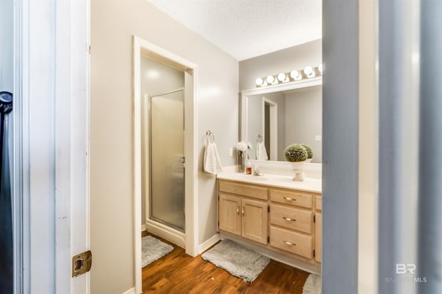 bathroom with a textured ceiling, a stall shower, wood finished floors, and vanity