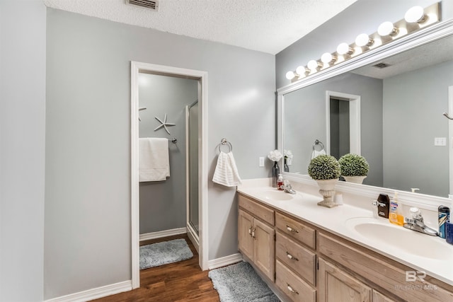 bathroom with double vanity, a sink, a textured ceiling, and wood finished floors